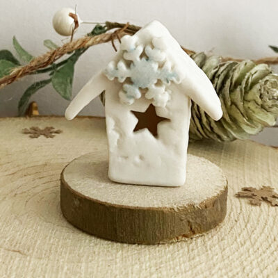 A mini snowflake house on a wooden base